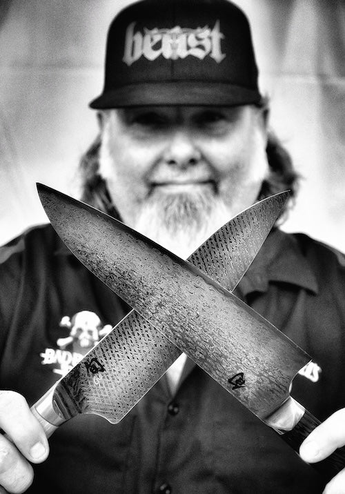 Brian Gurney of Bad Bones BBQ holding two Damascus chef knives